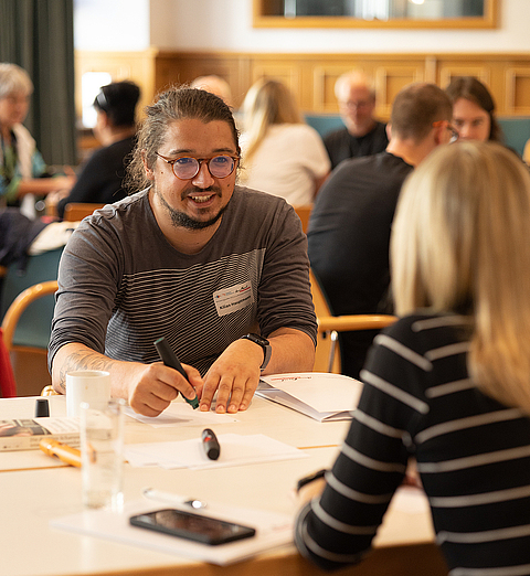 Zwei Personen sitzen sich an einem Tisch gegenüber.