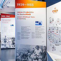 Mehrere Ausstellungswände mit Bild- und Texttafeln sowie Videos in DGS