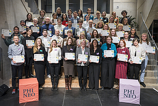 Gruppenfoto: Mehrere Reihen von Menschen, die alle eine Urkunde in der Hand halten
